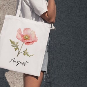May include: White tote bag with a pink watercolor poppy flower and the word "August" printed on it.