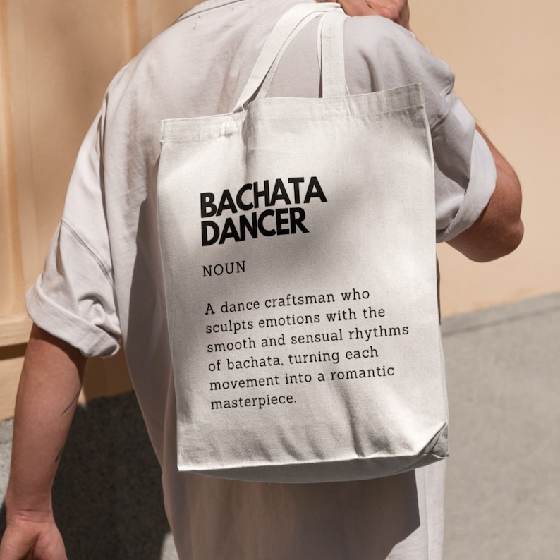 May include: White tote bag with black text that reads "BACHATA DANCER NOUN A dance craftsman who sculpts emotions with the smooth and sensual rhythms of bachata, turning each movement into a romantic masterpiece."