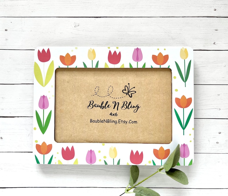 May include: White 4x6 picture frame with a floral design. The frame is decorated with colorful tulips in shades of pink, orange, red, and yellow. The frame includes a kraft-colored insert with the text 'Bauble N Bling', '4x6', and 'BaubleNBling.Etsy.com' printed on it. The overall theme is spring or floral.