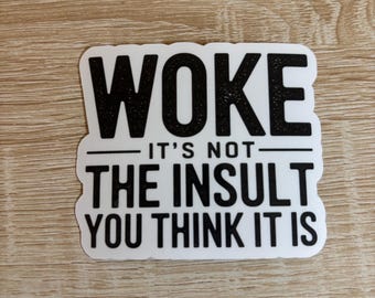 May include: White sticker with black text that reads "WOKE IT'S NOT THE INSULT YOU THINK IT IS"