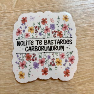 May include: A white sticker with a floral design and the text "Nolite Te Bastardes Carborundrum".