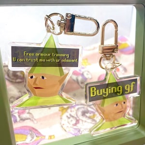 Może przedstawiać: Dwa zielone i żółte breloki z postaciami w pikselowym stylu, z łańcuszkiem ze złota. Pierwszy brelok przedstawia zielonego elfa z tekstem "Free armour trimming U can trust me with ur adamant". Drugi brelok przedstawia zielonego elfa z tekstem "Buying gf".