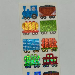 May include: Sheet of colorful train stickers. Designs include blue, yellow, green, and red locomotives and train cars. The stickers have a shiny, holographic finish, adding a playful touch to the designs. Great for crafts and decorating.