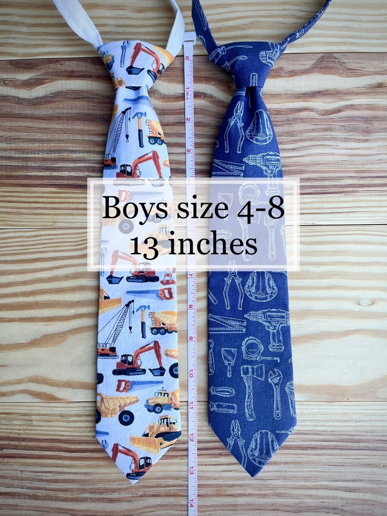 May include: Two boys' ties, one with a construction vehicle pattern and the other with a tools pattern. Both ties are 13 inches long and are suitable for boys sizes 4-8.