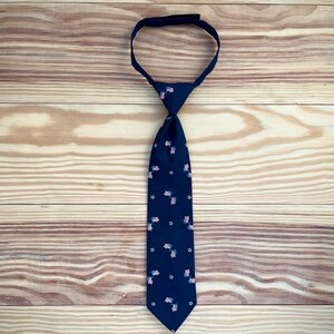 May include: A dark blue tie with a pattern of small American flags. The tie is made of a smooth fabric and has a classic design.