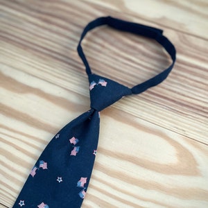 May include: A dark blue necktie with a pattern of small American flags and white stars.