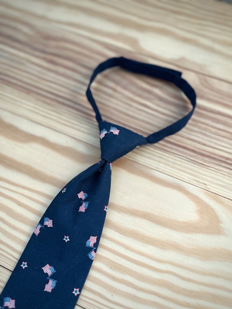 May include: A dark blue necktie with a pattern of small American flags and white stars.