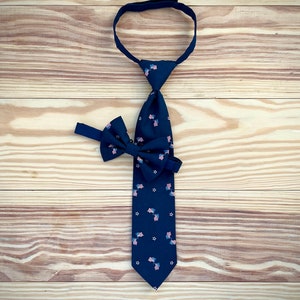 May include: A dark blue tie with a pattern of small American flags and white stars. A matching bow tie is also included.