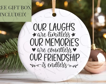 May include: A white ceramic Christmas ornament with black text that reads "OUR LAUGHS are limitless, OUR MEMORIES are countless, OUR FRIENDSHIP is endless." A gold ribbon is attached for hanging. The words "FREE GIFT BOX INCLUDED!" are in a green box.
