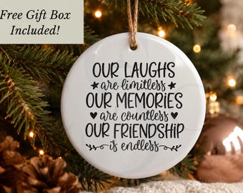 Pode incluir: Um ornamento redondo de cerâmica branca com texto preto que diz: Our laughs are limitless, our memories are countless, our friendship is endless. O ornamento está suspenso por um cordão castanho e apresenta estrelas, corações e espirais.