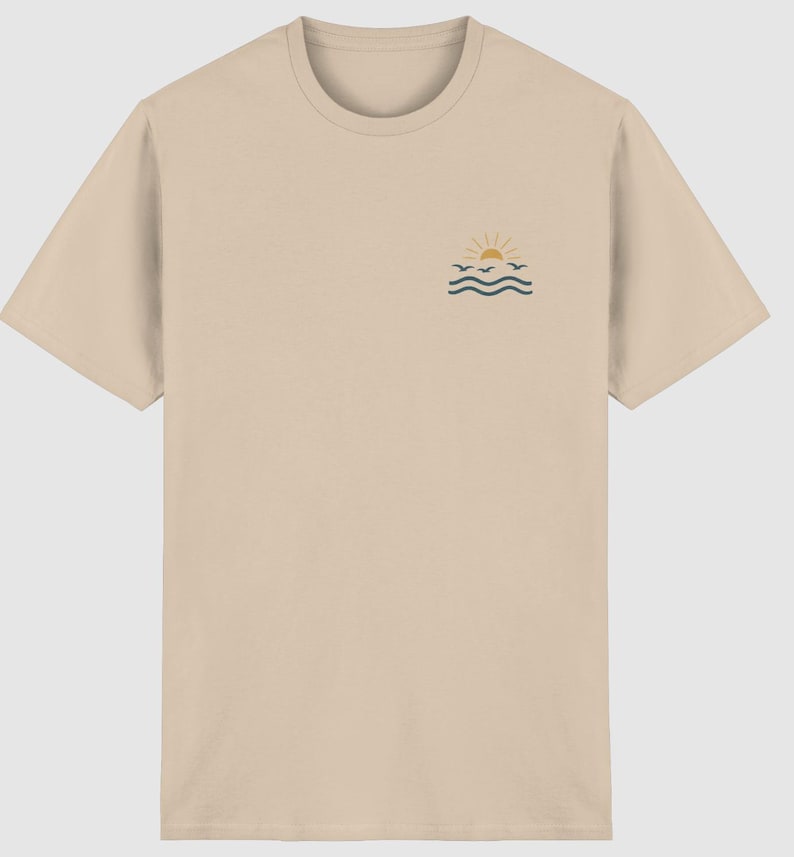 Pu&ograve; includere: Una t-shirt beige a maniche corte con una piccola grafica sulla parte superiore sinistra del petto. La grafica raffigura un sole giallo che sorge sopra onde marine blu scuro con tre piccoli uccelli blu scuro che volano tra il sole e le onde.
