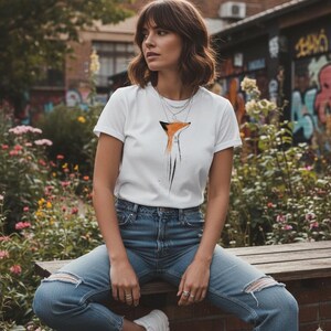 May include: A white short-sleeved t-shirt featuring a stylised orange and black fox graphic on the chest, paired with blue denim jeans that have distressed knee detailing. The t-shirt has a crew neckline and is worn with layered silver necklaces.