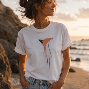 May include: A white short-sleeved t-shirt featuring a stylised graphic illustration of a fox head and neck in orange and black ink-wash style. The design is centred on the chest, showcasing a minimalist artistic depiction of the animal.