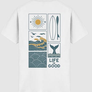 Pu&ograve; includere: Una t-shirt bianca con un design grafico sul retro composto da cinque pannelli rettangolari. I pannelli mostrano un sole, una tavola da surf, un'onda con uccelli, una coda di balena e un motivo a onde. Il testo LIFE IS GOOD &egrave; stampato in blu.