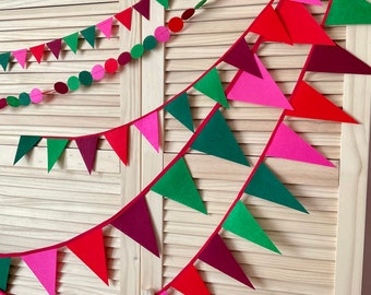 Könnte beinhalten: Eine festliche Girlande mit abwechselnd roten, grünen und pinkfarbenen Filz-Dreiecksflaggen. Die Girlande ist mit roten, grünen und pinkfarbenen Papierkreisen besetzt.