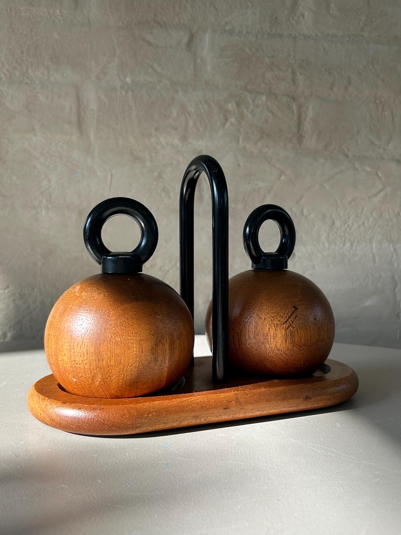 Close-up of teak spherical Bodum Ballboy salt and pepper grinders with cast iron handles, showing wood grain and vintage patina.
