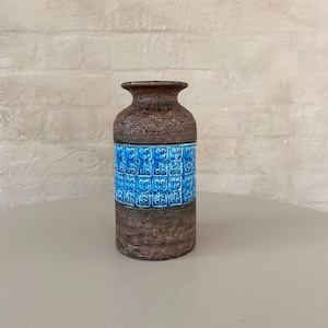 May include: A brown ceramic vase with a blue patterned band around the middle. The vase has a textured surface.