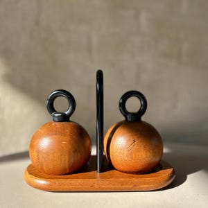 Vintage Bodum “Ballboy” salt and pepper grinders in teak with cast iron loop handles on teak stand, designed by R. Nissen, Made in Denmark.