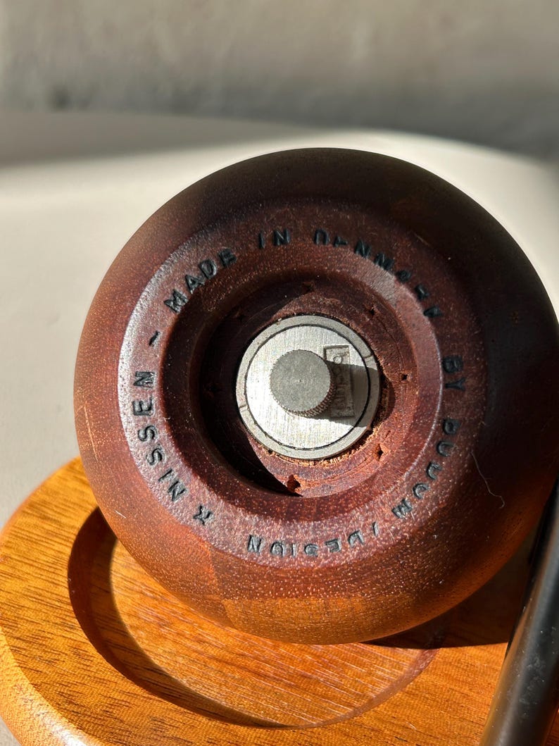 Close-up of base showing “Design R. Nissen Made in Denmark by Bodum” marking on vintage teak grinder.