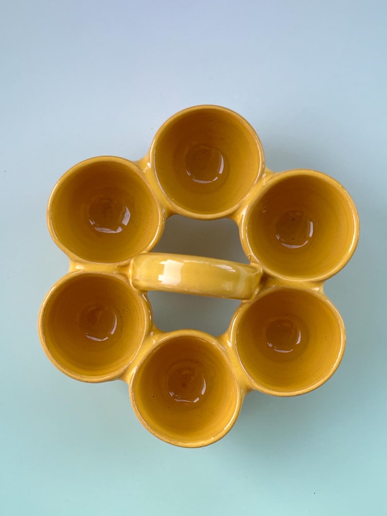 Puede incluir: Una fuente de cer&aacute;mica amarilla con siete compartimentos circulares dispuestos en forma de flor. La fuente tiene un asa y un acabado brillante. Los compartimentos est&aacute;n dise&ntilde;ados para contener peque&ntilde;as porciones de comida.