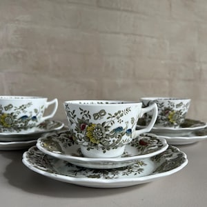May include: A set of three vintage teacups and saucers featuring a floral and bird design in shades of green, brown, yellow, and blue.