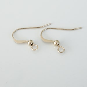 May include: Two gold-toned earring hooks with a small ball at the end of each hook.