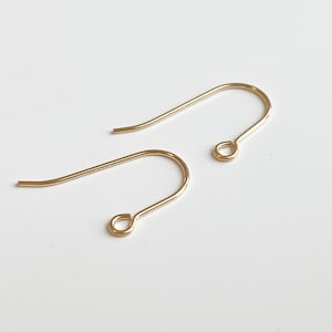 May include: Two gold-toned earring hooks. The hooks are made of metal and have a simple, elegant design.