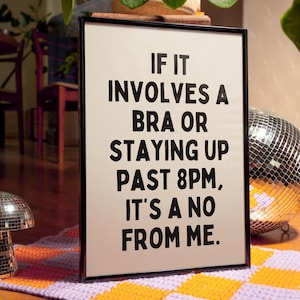 May include: A black framed sign with a white background and black text that reads "IF IT INVOLVES A BRA OR STAYING UP PAST 8PM, IT'S A NO FROM ME."