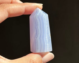 May include: A blue agate crystal point with white and light blue banding. The crystal is smooth and polished.