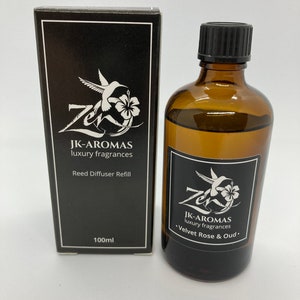 May include: A black and white label on a brown glass bottle with a black lid. The label reads "JK-AROMAS luxury fragrances •Velvet Rose & Oud.". The bottle is next to a black box with a white label that reads "JK-AROMAS luxury fragrances Reed Diffuser Refill 100ml".