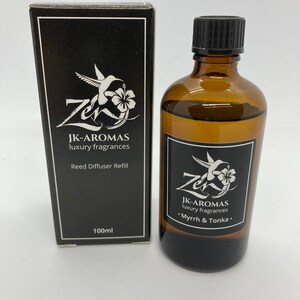 May include: A black and white box with a hummingbird logo and the text "JK-AROMAS luxury fragrances Reed Diffuser Refill 100ml". A brown glass bottle with a black cap and the text "JK-AROMAS luxury fragrances •Myrrh & Tonka."