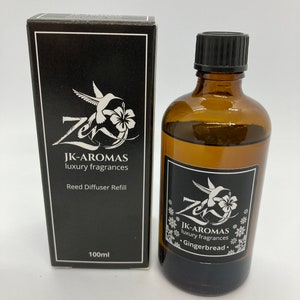 May include: A black box with a hummingbird and flower design and the text "JK-AROMAS luxury fragrances Reed Diffuser Refill 100ml". A brown glass bottle with a black cap and a label with a hummingbird and flower design and the text "JK-AROMAS luxury fragrances Gingerbread."