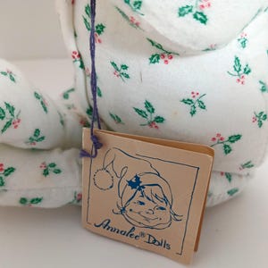 Pu&ograve; includere: Un set di tre tazze in ceramica con smalto screziato color crema. Ogni tazza presenta un design dipinto a mano diverso: una foglia blu e verde, un fiore giallo e una bacca rossa. Le tazze hanno una forma semplice e arrotondata.