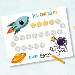 Op de afbeelding: Een witte beloningskaart met een ruimtethema. Het bevat een raket, astronaut, Saturnus, sterren en maan afbeeldingen. Tekst bevat "YOU CAN DO IT!" en "REWARD: Legos."