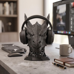 Könnte beinhalten: Eine mattschwarze, geometrische Drachenkopf-Skulptur, die als Kopfhörerständer dient. Der Drache weist scharfe, kantige Facetten und eine hohle Gitterbasis auf. Ein schwarzer Over-Ear-Kopfhörer liegt sicher auf dem Kopf des Drachen.