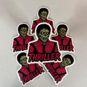 Może przedstawiać: Kolekcja naklejek przedstawiających postać zombie w czerwonej kurtce. Naklejki mają napis "Thriller" pogrubionymi, czerwonymi literami. Postać ma zieloną sk&oacute;rę, czarne włosy i ż&oacute;łte oczy.