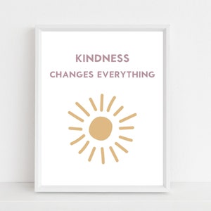 May include: A white framed print with the text "KINDNESS CHANGES EVERYTHING" in purple and a stylised sun in yellow.