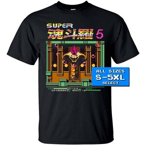 Puede incluir: Camiseta negra con un gráfico de videojuego retro que presenta una serpiente y el texto "SUPER 魂斗羅5" (Super Contra 5). El gráfico está en estilo pixelado e incluye el texto "LIFE 00126650 600×9 B055". La camiseta está disponible en tallas S-5XL.