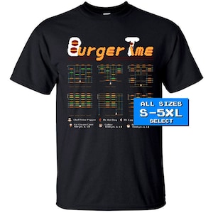 Könnte beinhalten: Schwarzes T-Shirt mit einem Pixelbild des Videospiels Burger Time. Das Bild enthält den Titel des Spiels, die Charaktere und eine Levelkarte. Der Text "ALL SIZES S-5XL SELECT" ist in Blau auf weißem Hintergrund gedruckt.
