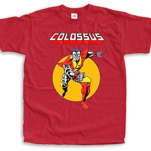 Könnte beinhalten: Rotes T-Shirt mit einer Comic-Illustration von Colossus. Die Grafik zeigt eine muskulöse Figur in einem gelben und roten Kostüm, vor einem gelben Kreis. Das Wort "COLOSSUS" ist in weißen Blockbuchstaben mit roten Umrissen gedruckt.