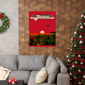 May include: A retro video game cover art print featuring a red background with the title "JACKAL" in white and blue letters. The image shows a sunset scene with three soldiers and a jeep driving towards a helicopter in the sky.