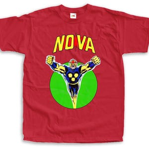Pode incluir: Camiseta vermelha com uma ilustração de banda desenhada de um super-herói. A palavra "NOVA" está em amarelo sobre um círculo verde. O super-herói é mostrado com os braços estendidos, numa pose dinâmica.