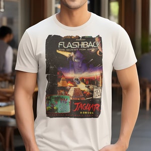 May include: White t-shirt featuring a retro-style graphic of the video game "Flashback: The Quest for Identity" for the Atari Jaguar.
