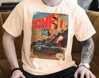 Puede incluir: Camiseta color crema con un gráfico de estilo vintage que representa un tanque disparando, helicópteros y la palabra "CONFLICT" en letras en negrita. El diseño tiene un aspecto envejecido y desgastado, con el logotipo de Nintendo en la parte inferior.