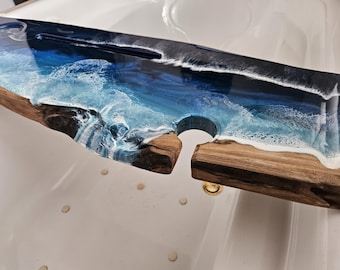 May include: A wooden serving tray with a blue and white epoxy resin top that resembles ocean waves. The tray has a cutout for holding wine bottles.
