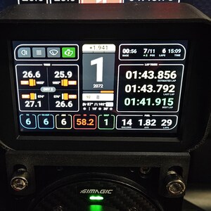 May include: A black racing simulator dashboard with a digital display showing race data, including lap times, fuel levels, and tire temperatures. The display also shows the driver's position, lap number, and race time. The dashboard is labeled "SIMAGIC".
