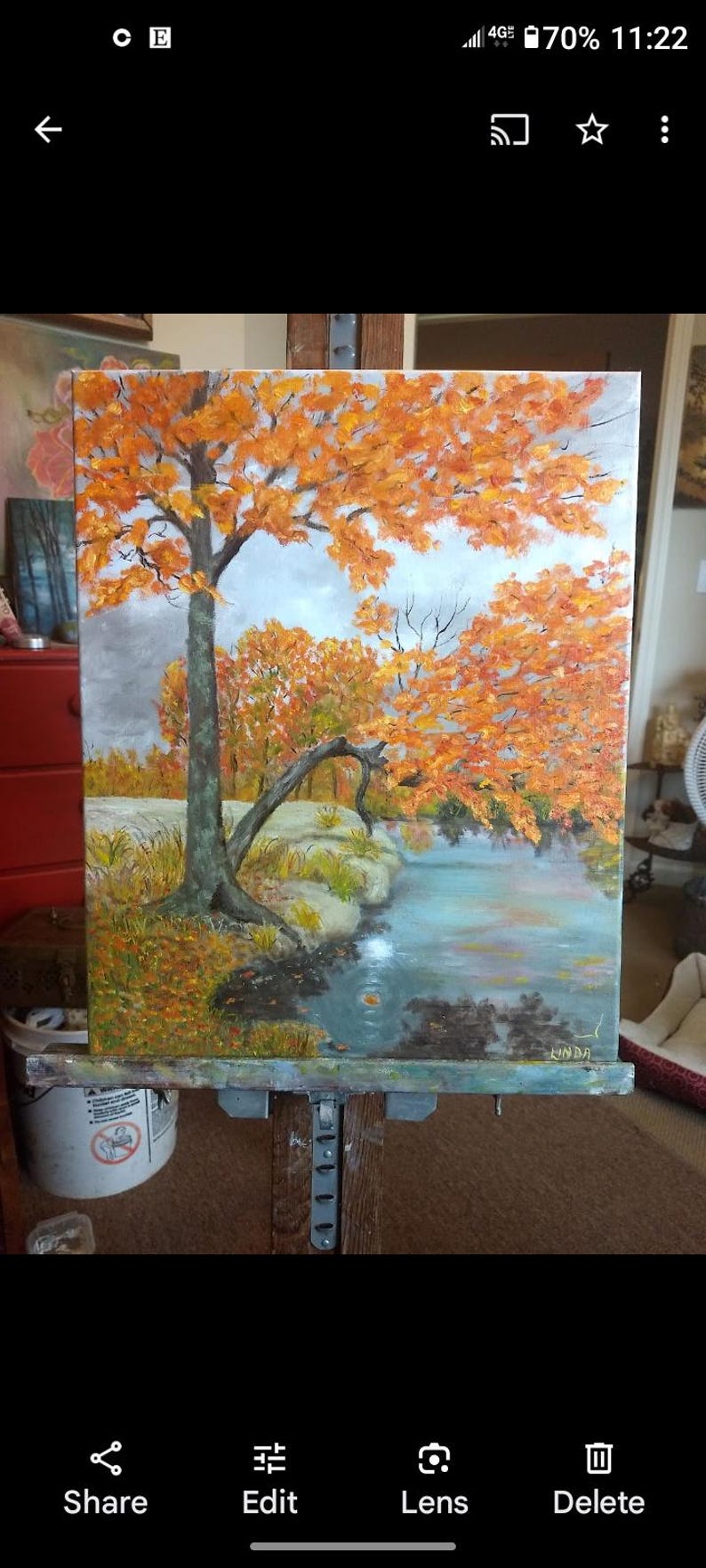 K&ouml;nnte beinhalten: &Ouml;lgem&auml;lde einer Landschaft mit einem Baum mit leuchtend orangefarbenen Bl&auml;ttern, die sich in einem blau-gr&uuml;nen Gew&auml;sser spiegeln. Das Kunstwerk, signiert mit "LINDA", zeigt eine Herbstszene unter bew&ouml;lktem Himmel.
