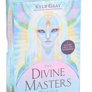 May include: A box for "The Divine Masters Oracle" deck. The box features a pastel illustration of a serene figure with long white hair and blue skin. The text "Kyle Gray" and "Artwork by Jennifer Hawkyard" are visible. The box also states "A 44-Card Deck and Guidebook".