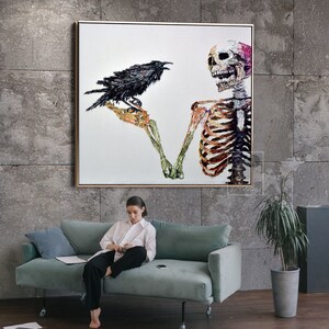 K&ouml;nnte beinhalten: Ein Gem&auml;lde, das ein Skelett mit einem Raben zeigt, der auf seinem Arm sitzt. Das Skelett ist in einem farbenfrohen, strukturierten Stil gemalt. Der Hintergrund ist wei&szlig;.