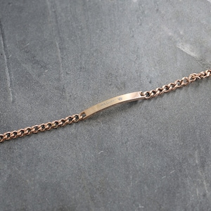 May include: Rose gold bracelet with a curb chain design. The bracelet features a rectangular bar with the inscription "His Queen" and a small crown symbol. The jewellery is displayed on a grey surface.